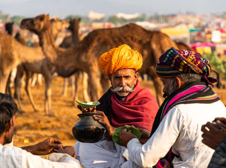 a old man drinking milk of camel.farmers and traders from all over the rajasthan flock for the annual fair.のeditorial素材