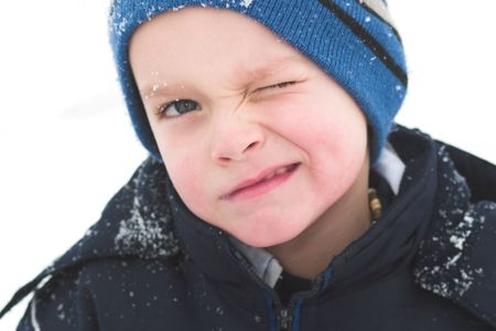 A child winks while playing in the snow.