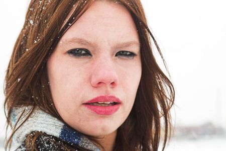 A young, beautiful woman stands outdoors as snow falls all around her.の写真素材