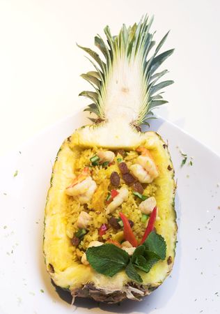 An exotic dish of fried rice inside a pineapple shell. The scattering of fine pieces around the dish is a part of the stylish of the dish.の写真素材