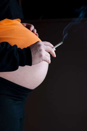 Shot of a pregnant woman smoking a cigaretteの写真素材