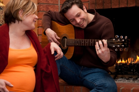 A happy father plays the guitar for his pregnant wifeの写真素材