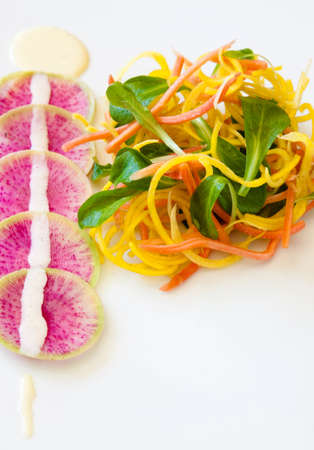 Beautiful salad made from golden beets, red carrots, valentine radish, lamb's lettuce, honey horseradish emulsion and pistachio dustの写真素材