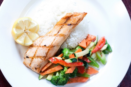 Fillet of salmon baked with our maple glaze, served on a bed of aromatic basmati rice with stir fry vegetables.の写真素材