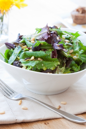 Garden greens salad made with fresh lettuce and spinach. Topped with kalamata olives, pine nuts and drizzled with balsamic vinaigrette.の写真素材