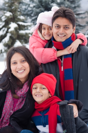 A beautiful East Indian parents play with her children in the snow.の写真素材