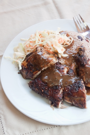 Caribbean style jerk chicken served with rice mixed with red kidney beans. Dish accompanied with coleslaw. Shallow Focus on the chicken.の写真素材