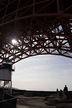Silhouettes of people looking out to the ocean from beneath the bridge