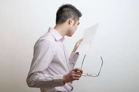 Head and shoulders of an Asian man looking at a letter that has been left blank.の写真素材