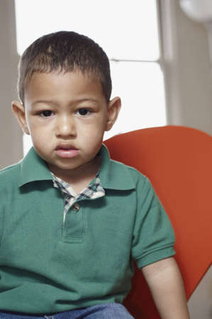 Mixed race toddler sitting and looking sullen