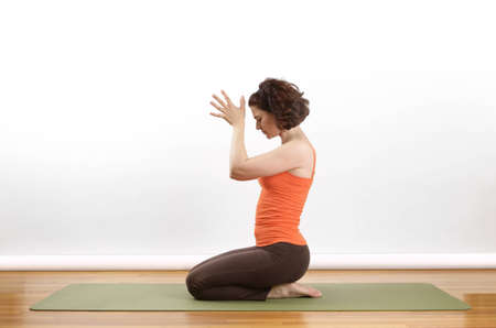 Woman showing  a Anjili Mudra yoga pose on a green matの写真素材