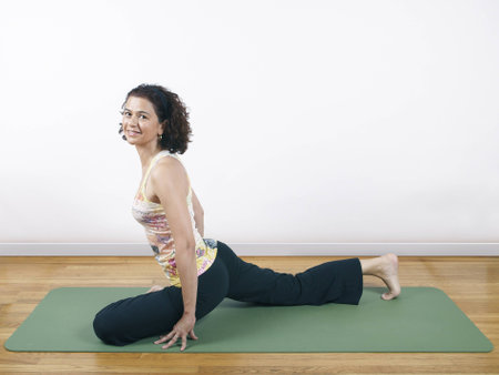 A woman holding a yoga pose on a floormatの写真素材
