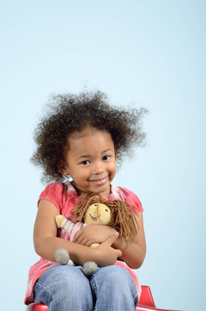 Little girl sitting and hugging a rag dollの写真素材