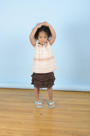 Mixed race little girl with her hands on her headの写真素材