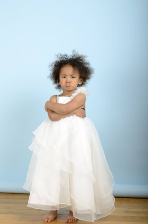 Little girl in white dress is not at all happyの写真素材