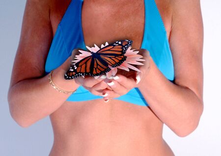 a pair of cupped female hands with flower and butterflyの写真素材