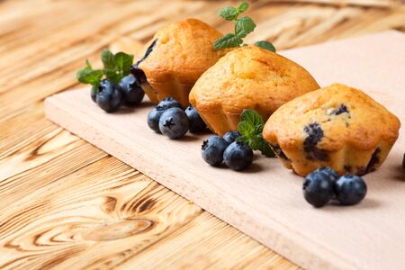 Homemade baked muffin with blueberries, fresh berries, mint on wooden background. Empty space for text. Top view. Delicious dessert. Fruit cupcake. Bakery banner, flyer, card. Empty space for text.の写真素材