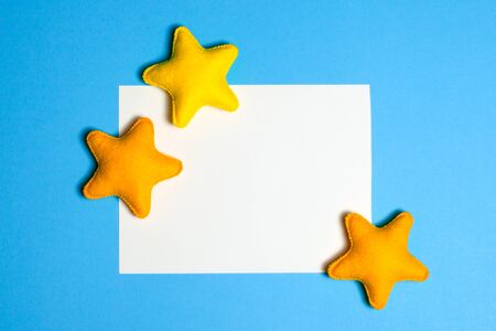 Craft yellow stars in blue sky with frame, copyspace. Hand made felt toys. Abstract sky. Concept for travel agency, motivation, business development, greeting card, banner, flyer.の写真素材