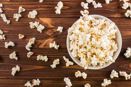 Popcorn horizontal banner. Red stripped paper cup and kernels lying on dark brown wooden background. Copy space. Top view. For cinema card, flyer, invitation.の写真素材