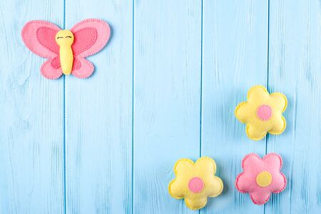 Craft pink and yellow butterfly and flowers with white paper, copyspace on blue wooden background. Hand made felt toys. Abstract sky. Concept for travel agency, greeting card, banner, flyer.の写真素材