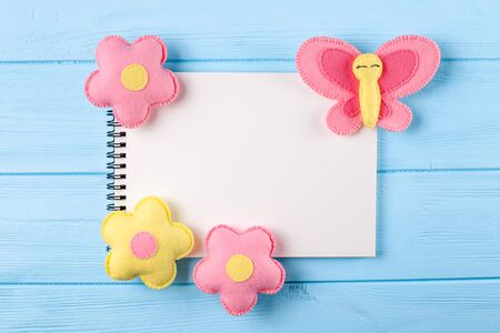 Craft pink and yellow butterfly and flowers with white paper, copyspace on blue wooden background....