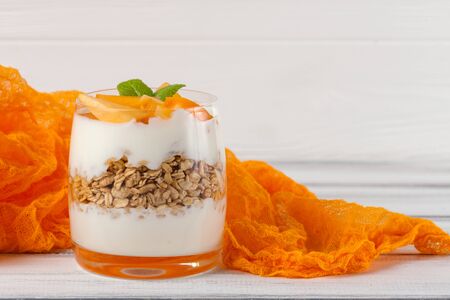 Persimmon creamy trifle in beautiful glasses, fresh ripe fruit slices on white wooden background. Healthy vegetarian food. Delicious dessert. Close up photography. Selective focus. Horizontal banner.の写真素材