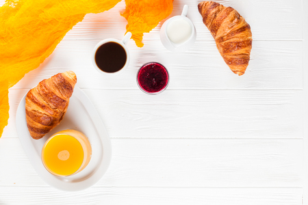 Freshly baked croissant orange juice, jam, cup of black coffee on white wooden background. French breakfast. Fresh pastries for morning. Delicious dessert. Closeup photography. Horizontal banner.の写真素材