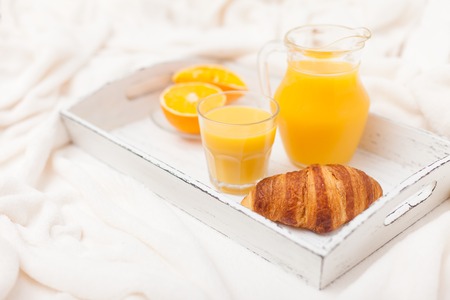 Freshly baked croissant, orange juice, jam, cup of black coffee on white wooden tray on plaid. Homemade cookie. Fresh pastries for breakfast. Delicious dessert. Closeup photography. Horizontal banner.の写真素材