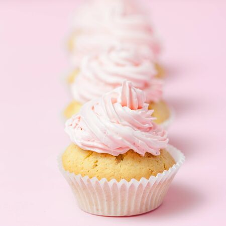 Cupcake decorated with pink buttercream on pastel pink background. Sweet beautiful cake. Square banner, greeting card for birthday, wedding, women's day. Close up photography. Selective focus.の写真素材