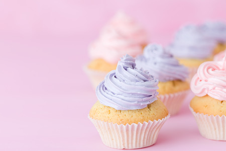 Cupcakes with pink and violet buttercream standing on pastel pink background. Sweet beautiful decorated cakes. Horizontal banner or greeting card for birthday wedding mothers day.の写真素材