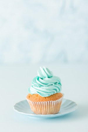 Cupcake with blue cream decoration on plate - beautiful blue pastel vertical banner with dessert and copy space for wedding or birthday party invitation, congratulation card, valentine, mothers day.の写真素材