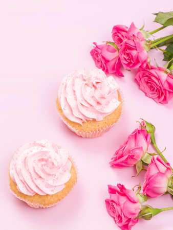 Cupcake with pink cream decoration and roses on pink pastel background - romantic horizontal banner for congratulation, greeting card for birthday, wedding, valentine or women day.の写真素材