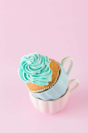 Cupcake with gentle blue cream decoration in two cups on pink pastel background - banner for wedding or birthday party invitation, congratulation card, valentine or mothers day.の写真素材