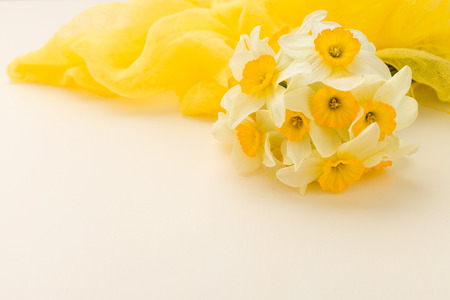 White daffodil bouquet with yellow textile decoration on pastel background with copy space. Closeup...
