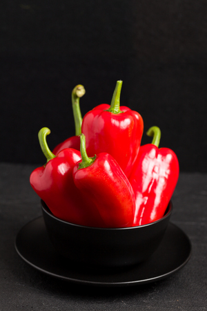 Red peppers in plate on blackの写真素材