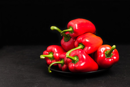 Red peppers in plate on blackの写真素材