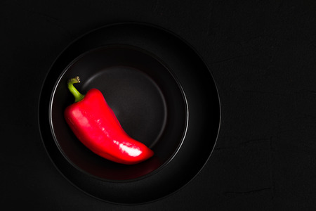 Red pepper in plate flat lay on blackの写真素材