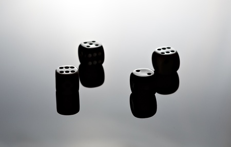 Four dice reflecting on black surface.の写真素材