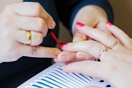 Manicure making - female hands covering of red enamelの写真素材