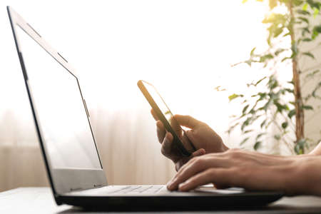 Man use smartphone and laptop in office or at home.