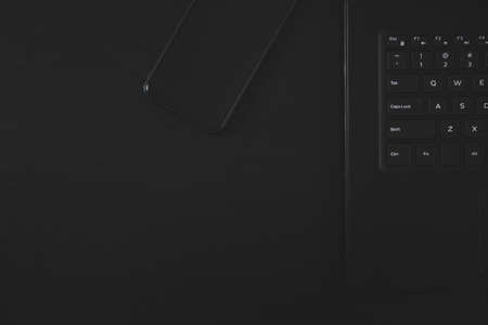 Black laptop and black smartphone on black table.の写真素材