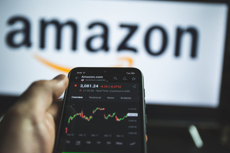 Holding mobile phone with stock market charts of Amazon company sharesのeditorial素材