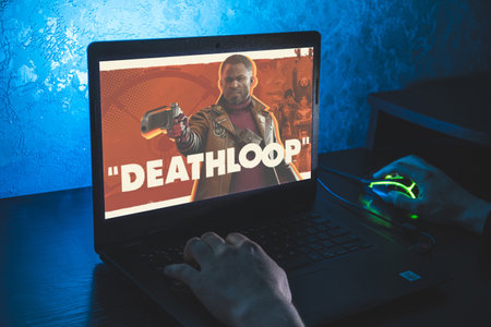 Deathloop is a 2021 action-adventure game. Video computer game. Man play video game on laptopのeditorial素材