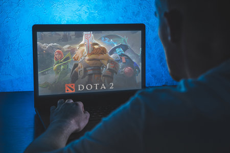Dota 2 is a multiplayer online battle arena video game. Video computer game. Man play video game on laptopのeditorial素材