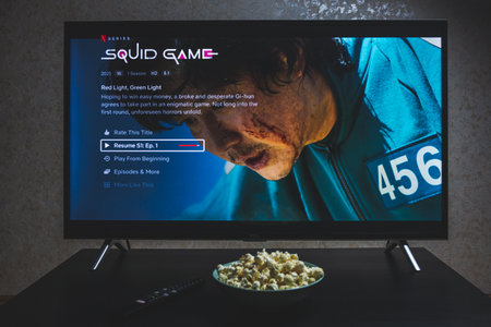 Watching Squid game show on TV. Squid game is a South Korean survival drama television series streaming on Netflixのeditorial素材