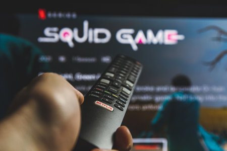 Watching Squid game show on TV. Squid game is a South Korean survival drama television series streaming on Netflixのeditorial素材
