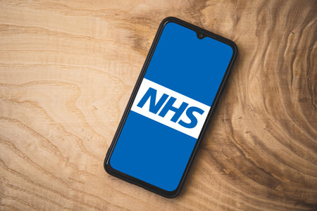 NHS application on smartphone. Wooden background. Top angle shotのeditorial素材