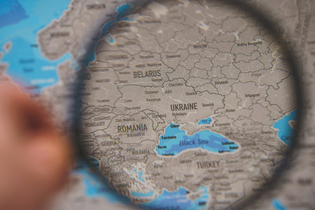 Ukraine on map. Ukraine through magnifying glass on paper map. Ukraine in Europe near Russia borderのeditorial素材