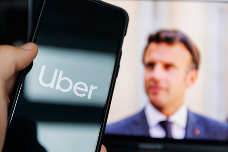 Uber app on mobile screen and Emmanuel Macron in background. Uber leak scandal