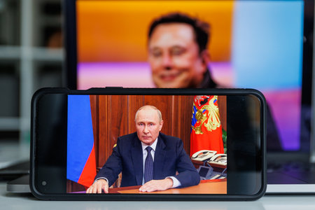Vilnius, Lithuania - 2022 October 13: Elon Musk on screen and Vladimir Putin in backgroundのeditorial素材